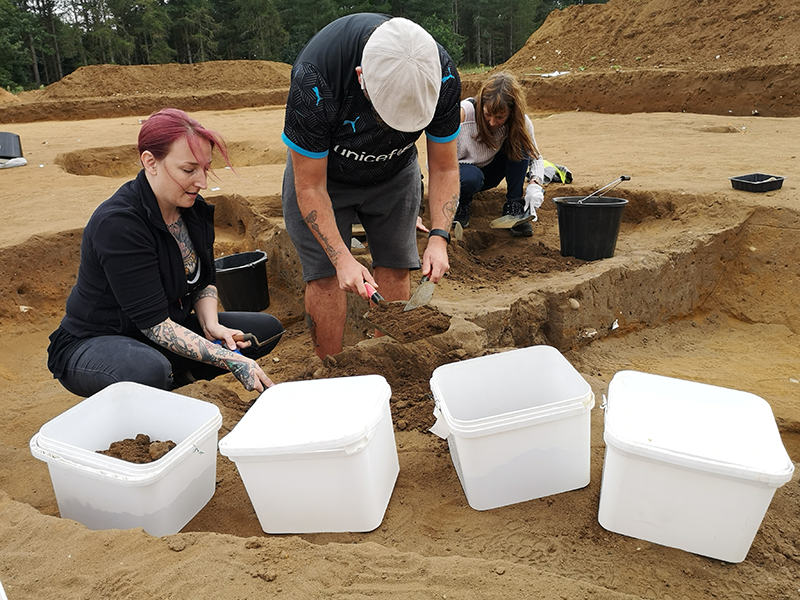 two people putting soil in white buckets