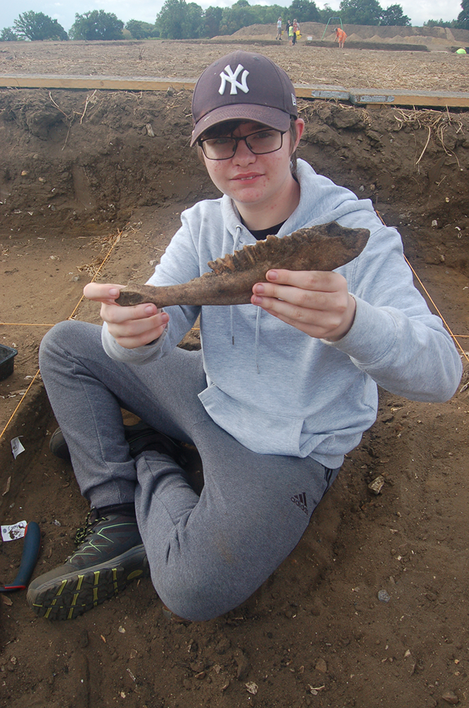 boy holding animal jaw sitting in trench