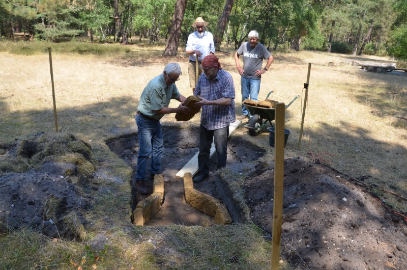 Four people building a pottery kiln